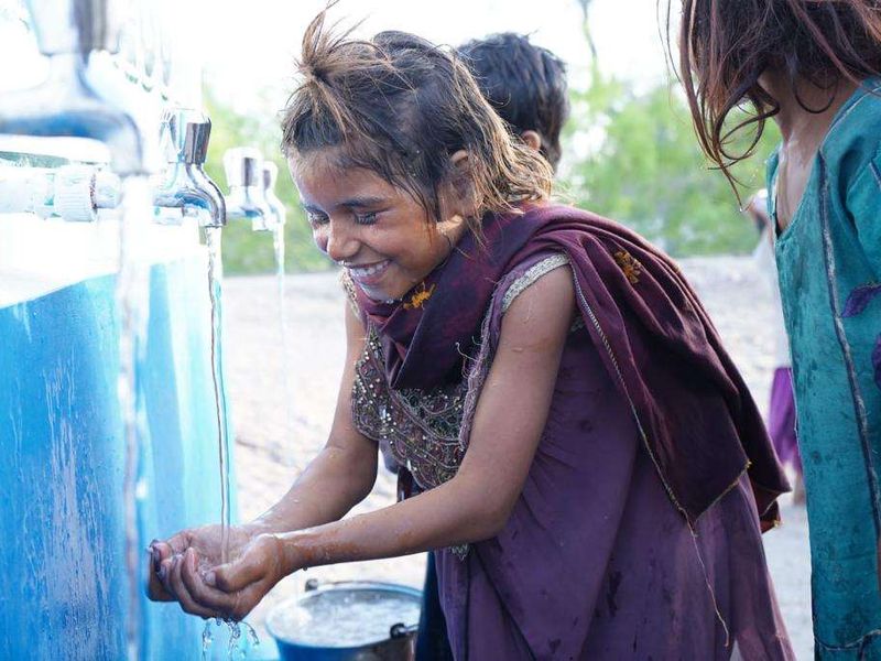 A girl washing at a water tank in Pakistan