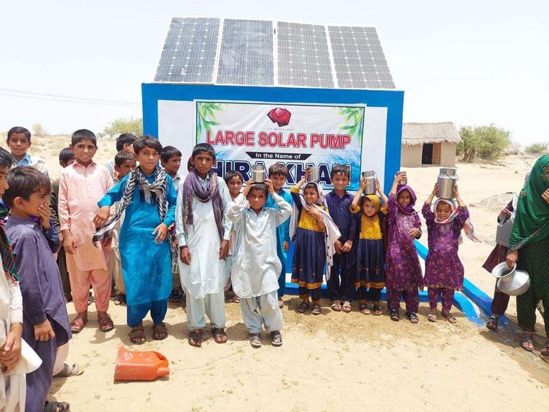 Children filling vessels at a large solar pump
