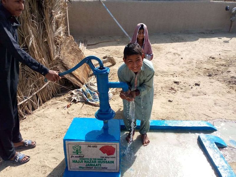 A boy drinking from a hand pump in Pakistan
